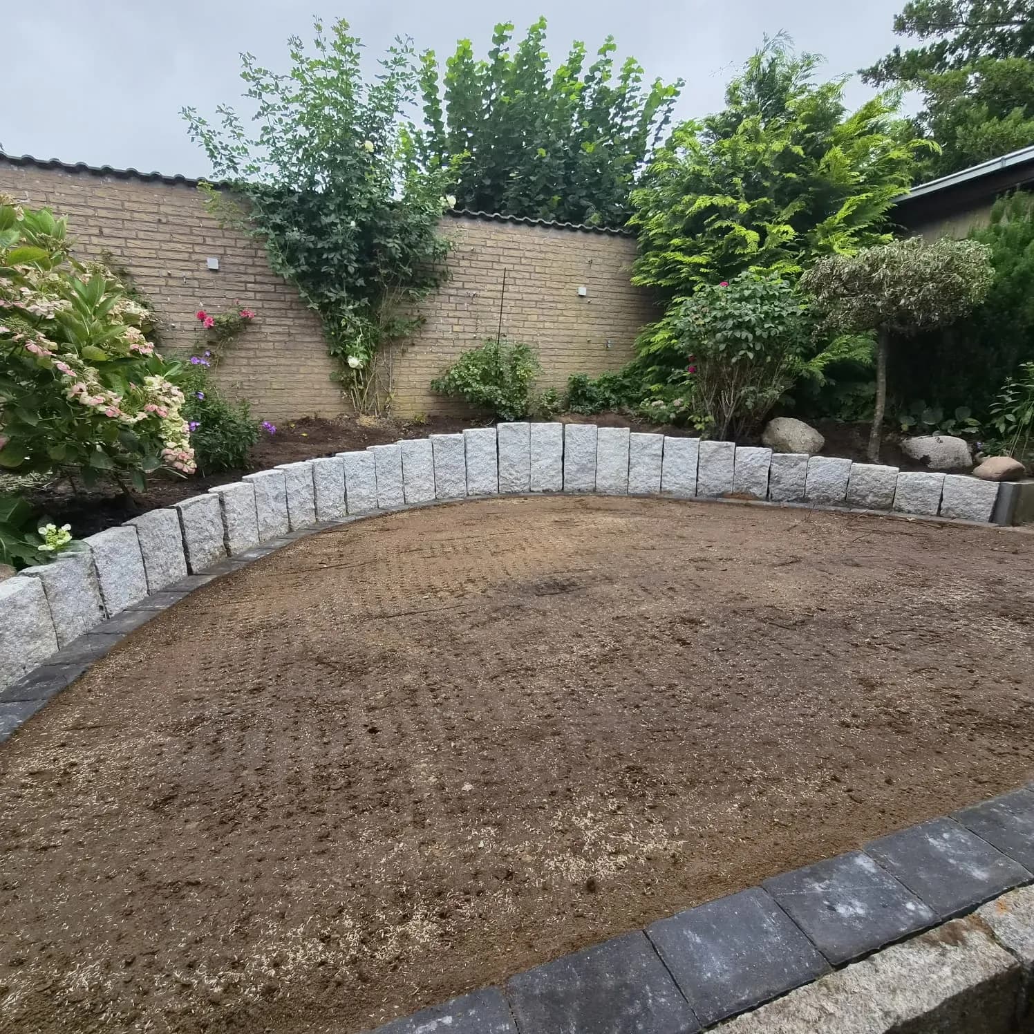 Nachher: neu angelegte Beetfläche mit geschwungener Granit-Randeinfassung und vorbereitetem Boden – Garten- und Landschaftsbau Asmussen